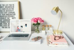 MacBook Air beside gold-colored study lamp and spiral books